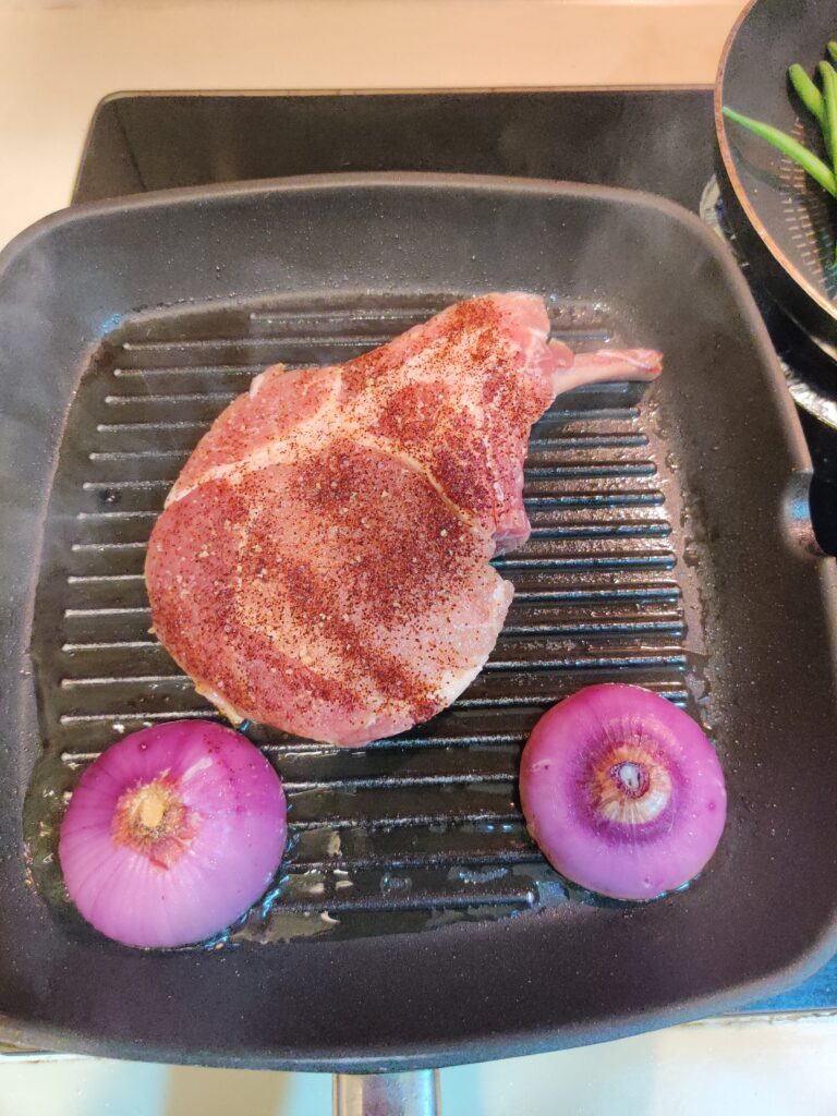 a photo of my tomahawk pork chop grilling on the pan